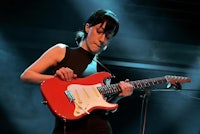 a woman playing a red electric guitar on stage